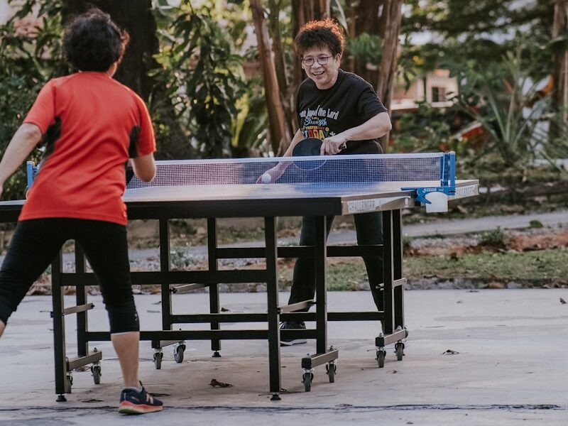 man in red crew neck t-shirt standing beside blue table during daytime Ping Pong Online