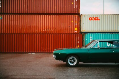 a green car parked in front of a shipping container