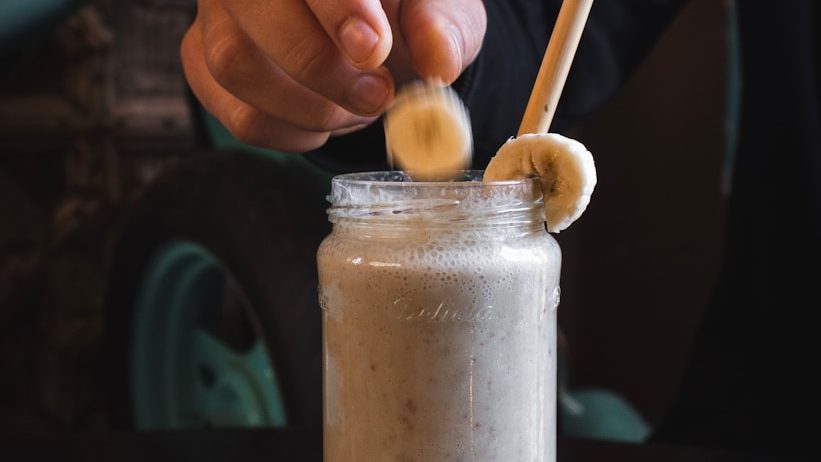 person putting sliced banana fruit on top of jar