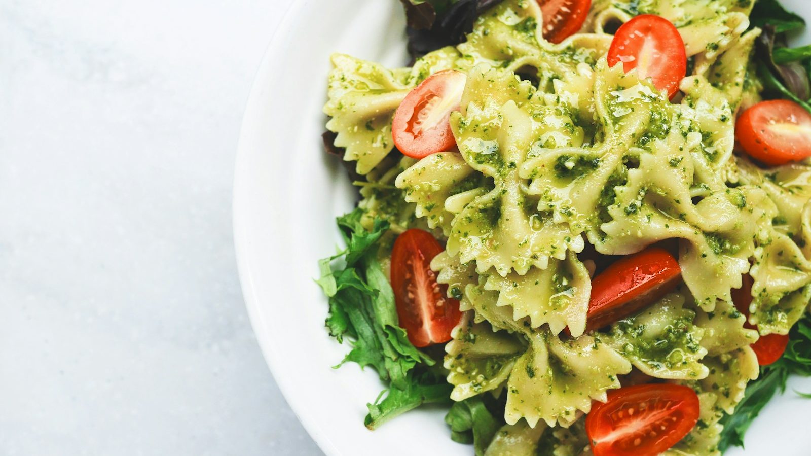 Pesto pasta with sliced tomatoes served on white ceramic plate. 10 Unbelievably Easy Recipes for Busy Weeknights