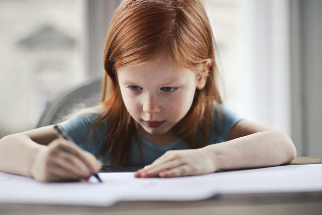 Girl Writing on Paper. 7 Simple Ways to Make Homework Less Stressful for Kids