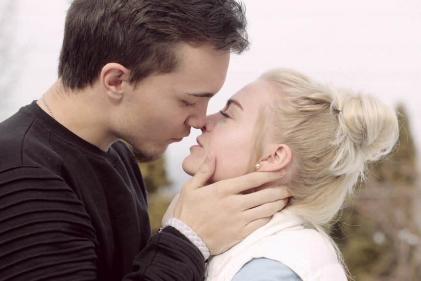 man wearing black top about to kiss woman