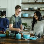 smiling man standing and mixing near woman in kitchen area of the house