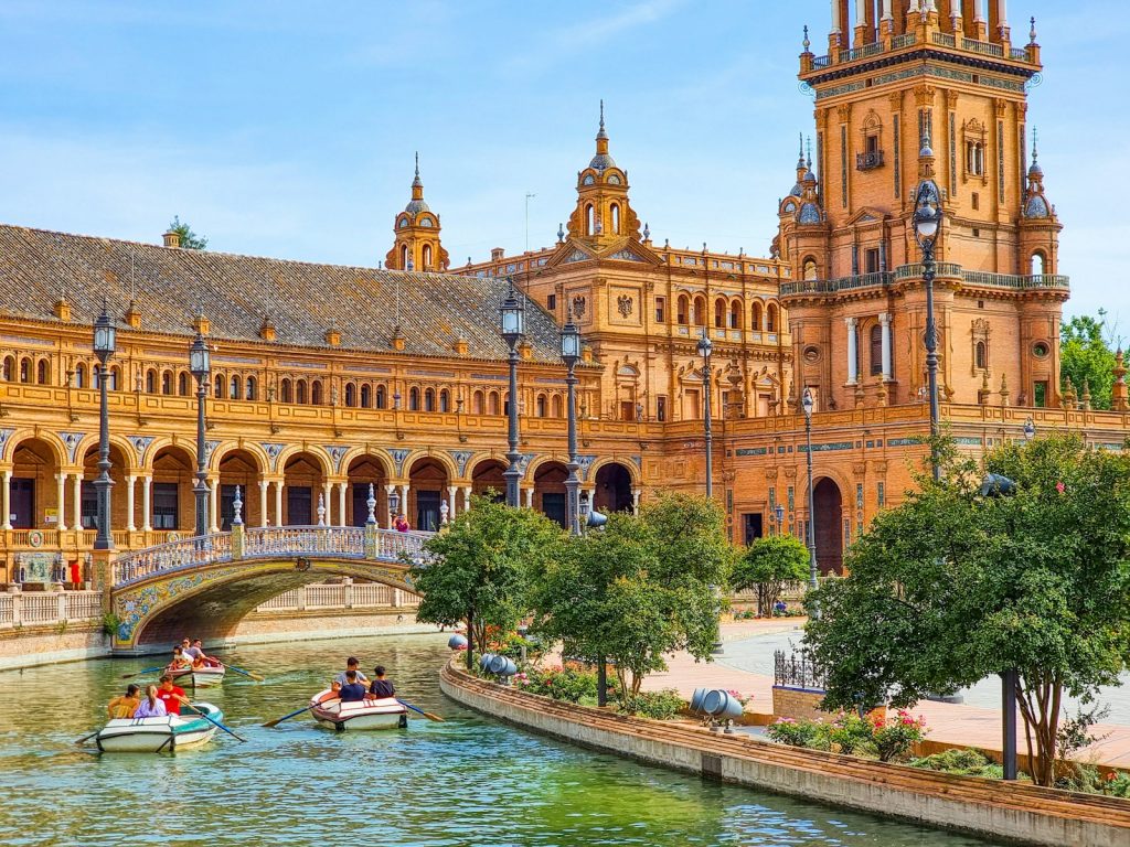 a group of people in a boat in a river in front of a large building