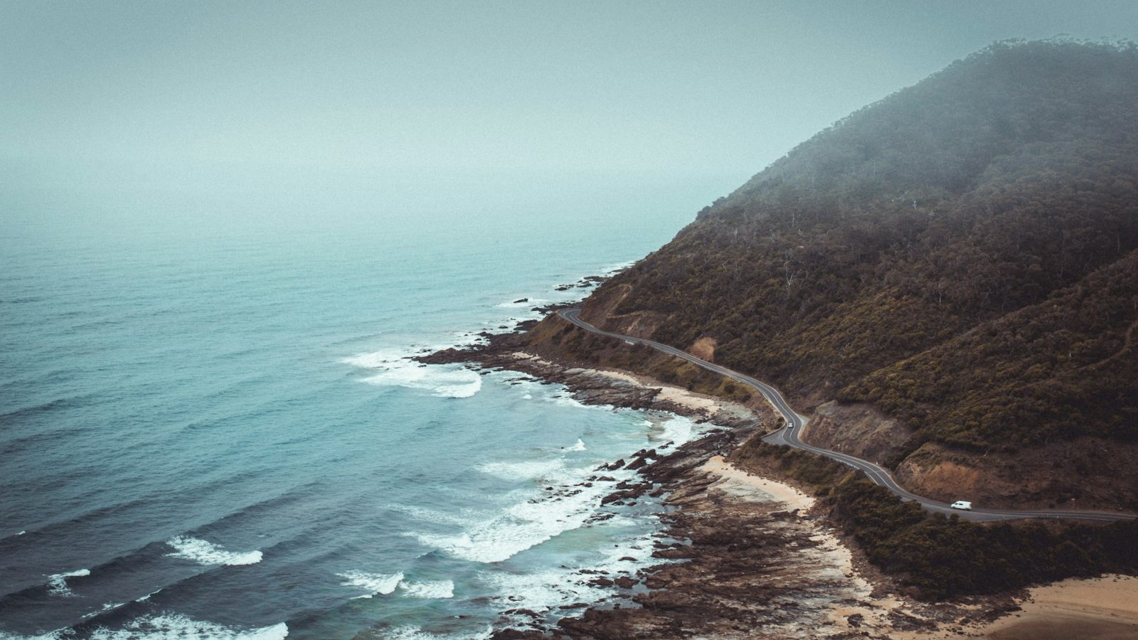 aerial photography of mountains beside road and sea. 7 Breathtaking Road Trips That Will Inspire Your Next Adventure