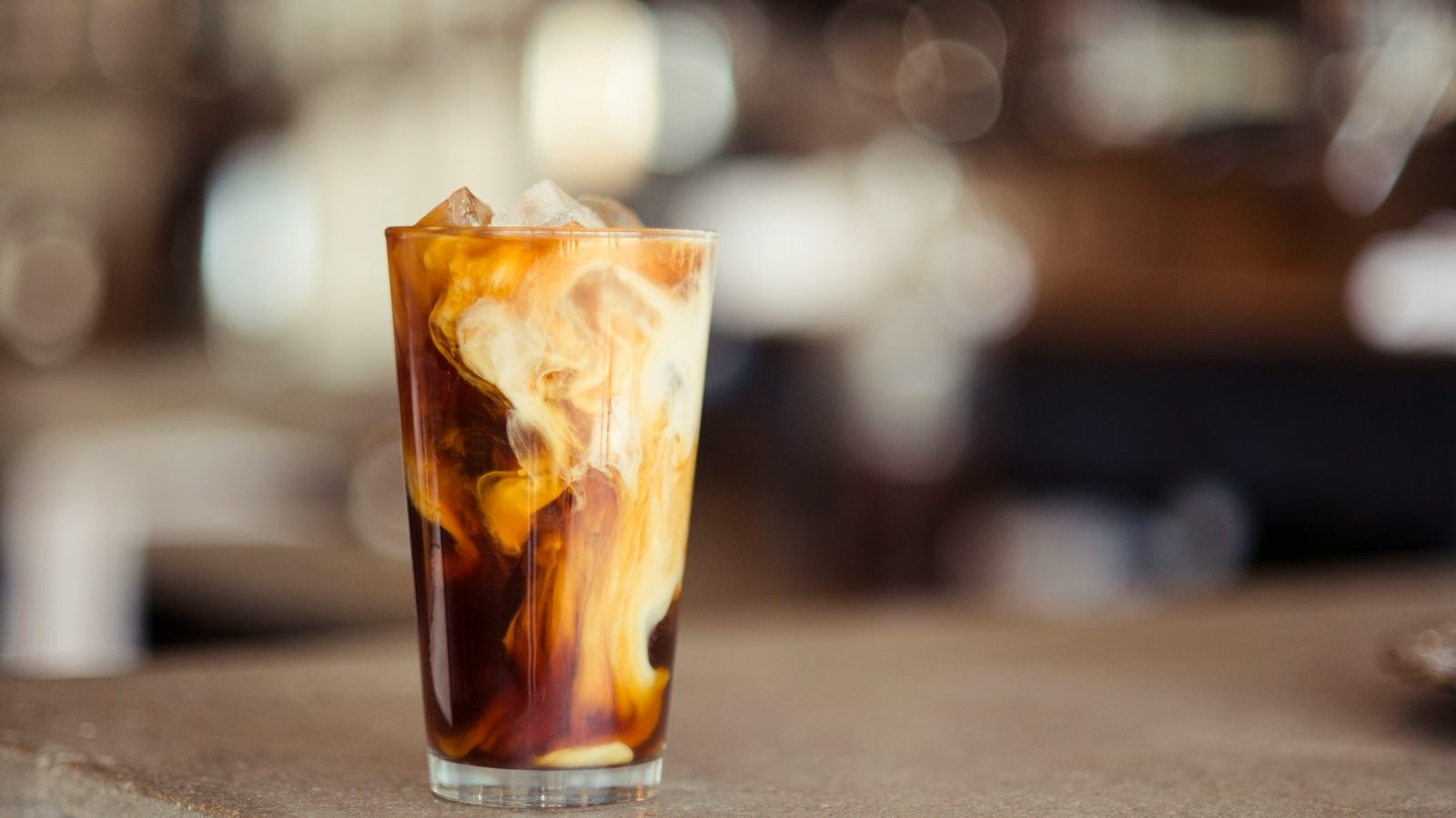 glass cup filled with ice latte on tabletop. 7 Incredible Coffee Shops You Need to Visit