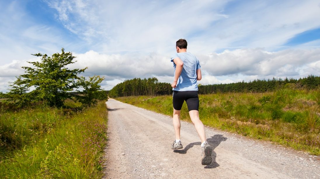 man running on road near grass field