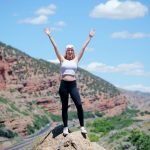 woman wearing white top and black pants standing on cliff