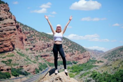 woman wearing white top and black pants standing on cliff