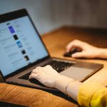 person using macbook pro on brown wooden table