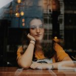 woman sitting next to table with hands on cheek