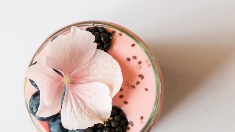 pink beverage on glass with blackberries and pink flower on top