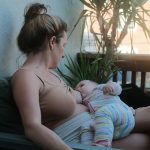 a woman sitting on a bench holding a baby