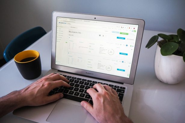 person using macbook air on white table