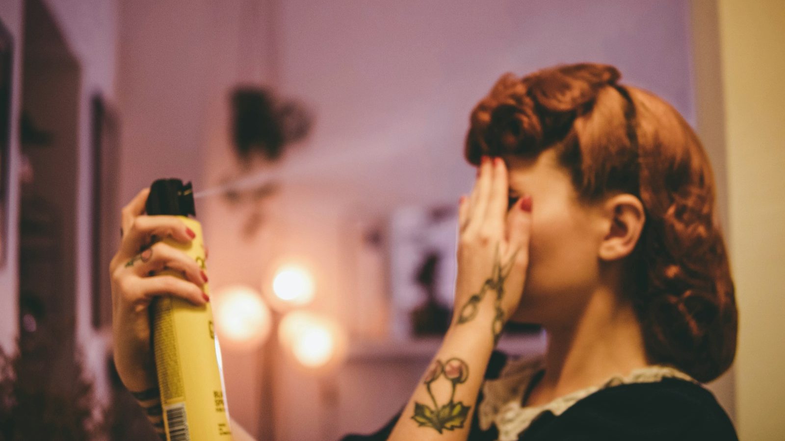 woman in black and white floral shirt holding yellow and black spray bottle