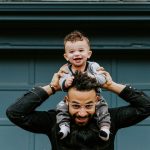 man in black leather jacket carrying boy in black leather jacket