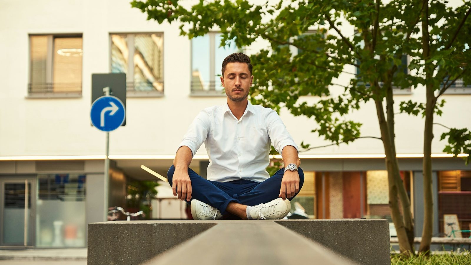 man in white dress shirt sitting on gray concrete bench during daytime