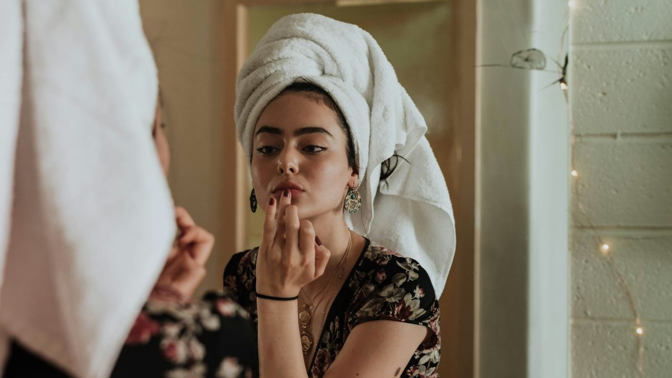 woman putting makeup in front of mirror, 5 Life-Changing Skincare Tips for Flawless Skin