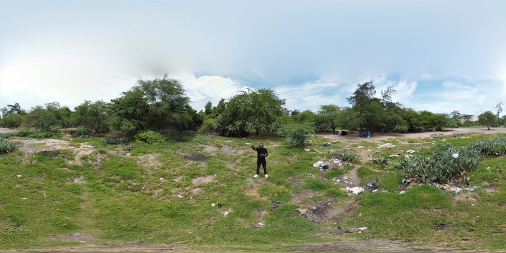 a man standing on a lush green field next to a forest