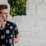 man in black top calling beside wall