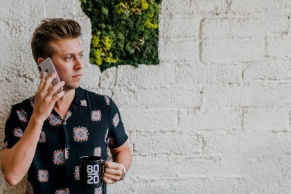 man in black top calling beside wall