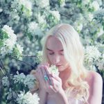 woman smelling flower during daytime