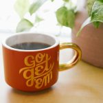 orange and white ceramic mug near green leaf plant with brown potted