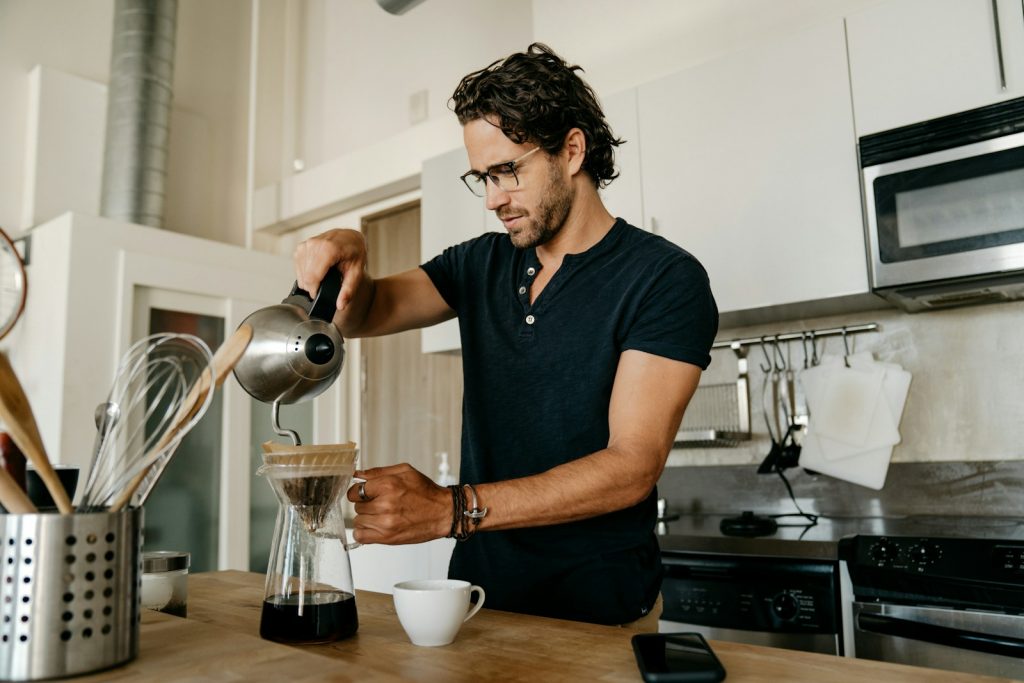 man in blue crew neck t-shirt pouring water on white ceramic teacup Top 10 Morning Routine Tweaks That Boost All-Day Energy