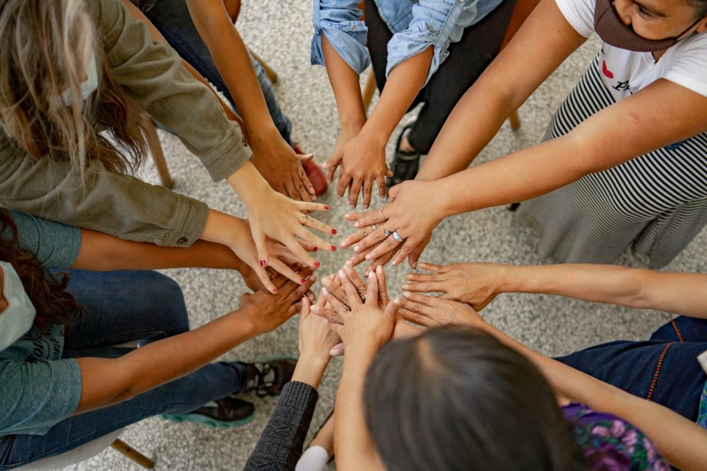 A group of people standing in a circle with their hands together Designing Metrics Creating Shared Goals