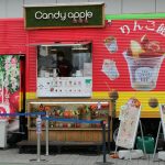 A candy apple food truck with japanese text.