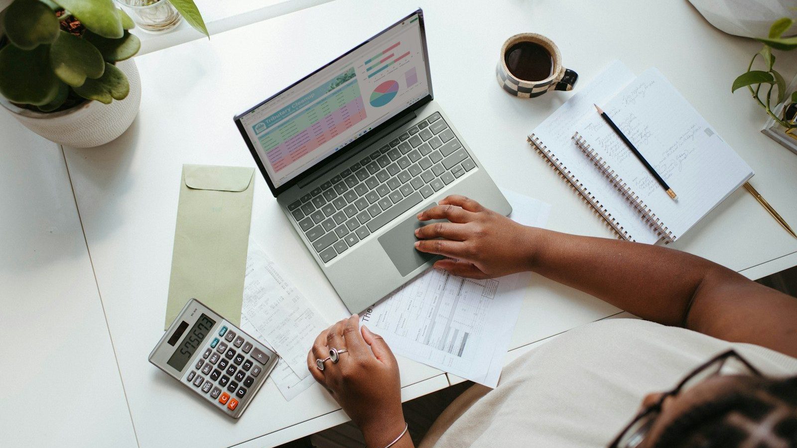 a person sitting at a table with a laptop Budget Financial Mistakes