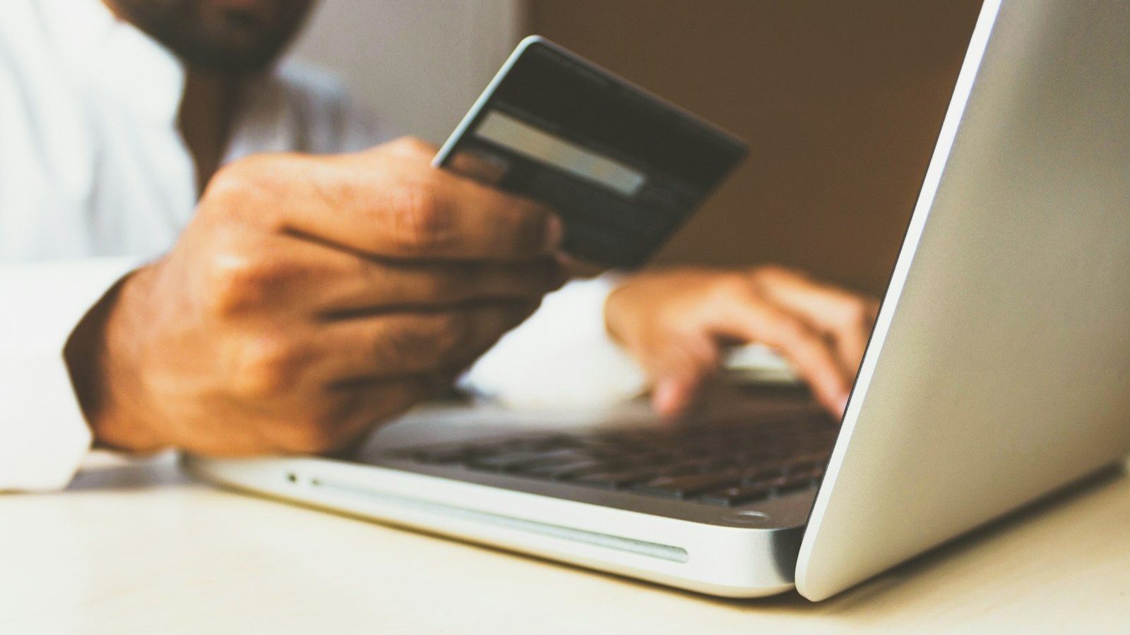 person using laptop computer holding card Customer Payment Policies Financial Mistakes