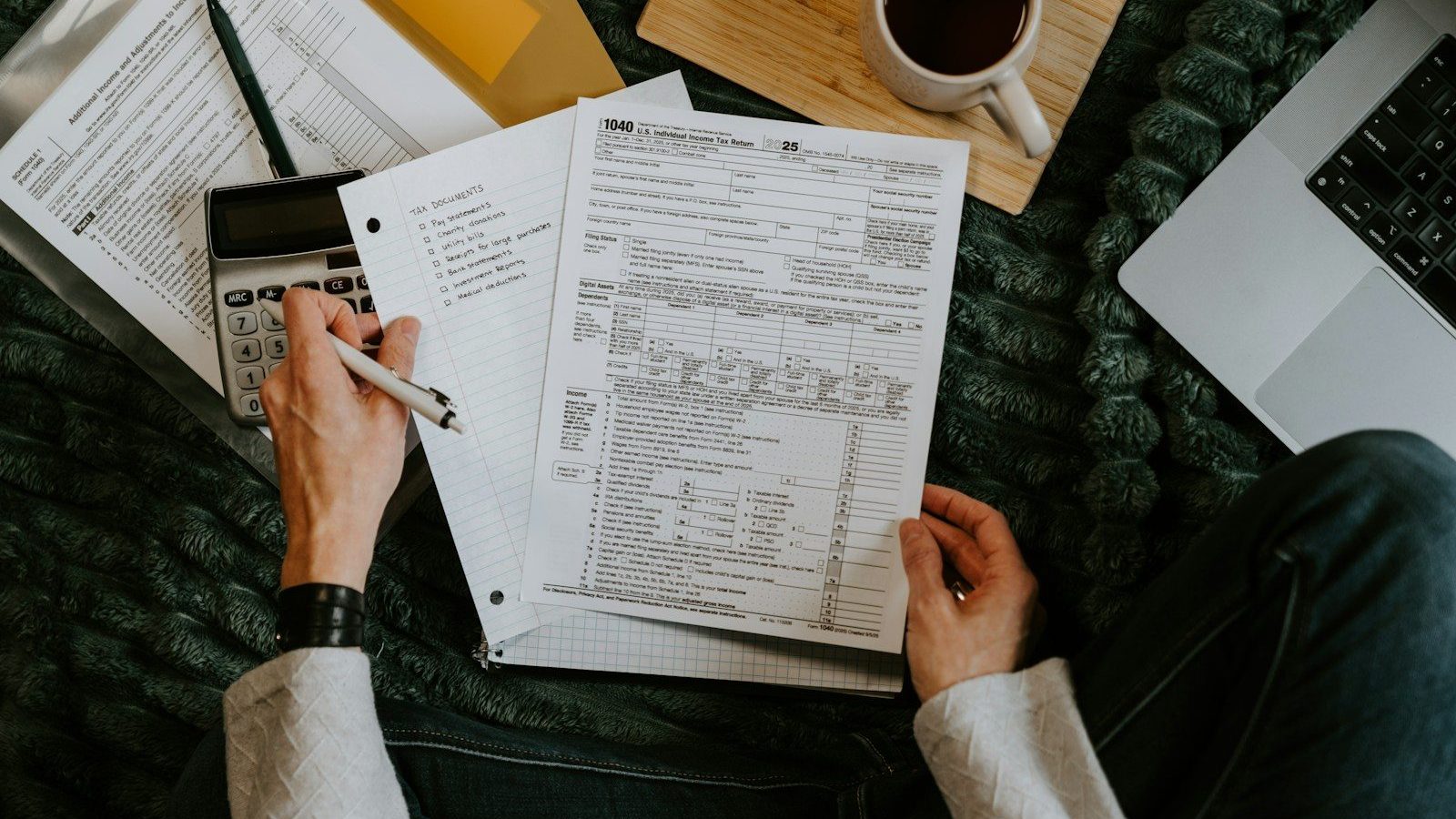 Person reviewing documents with calculator and laptop. Understand Taxes Hidden Fees in Contracts