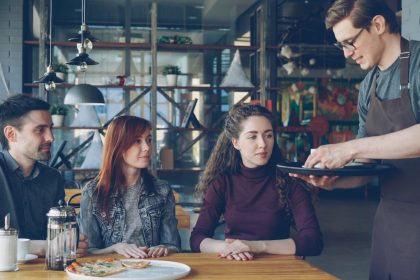 A waiter serves food to a couple in a restaurant.