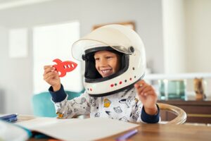 Child playing with astronaut helmet and rocket