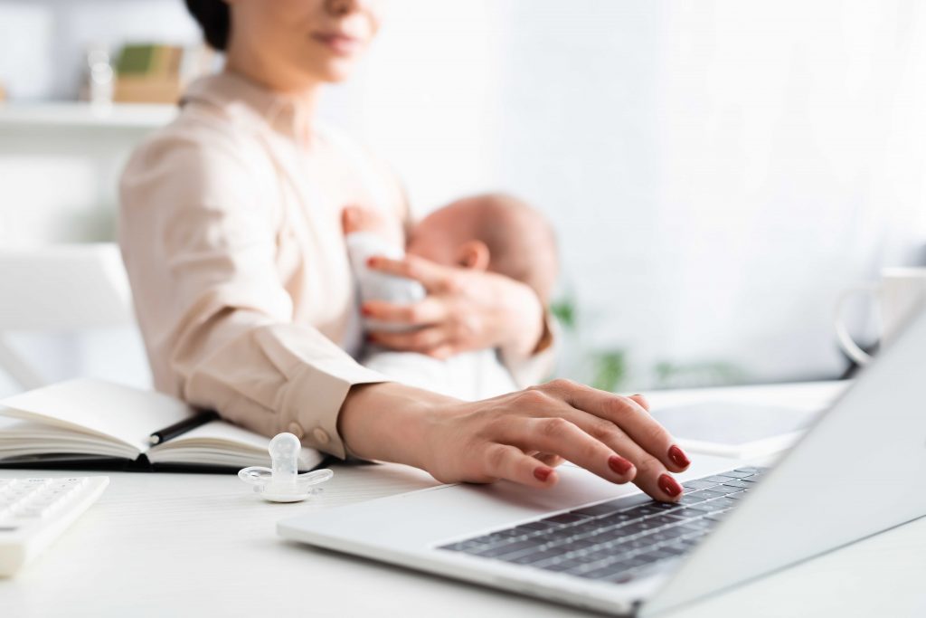 selective focus of mother breastfeeding infant son while working from home with laptop Wiedereinstieg als Steuerfachangestellte