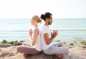 smiling couple making yoga exercises outdoors