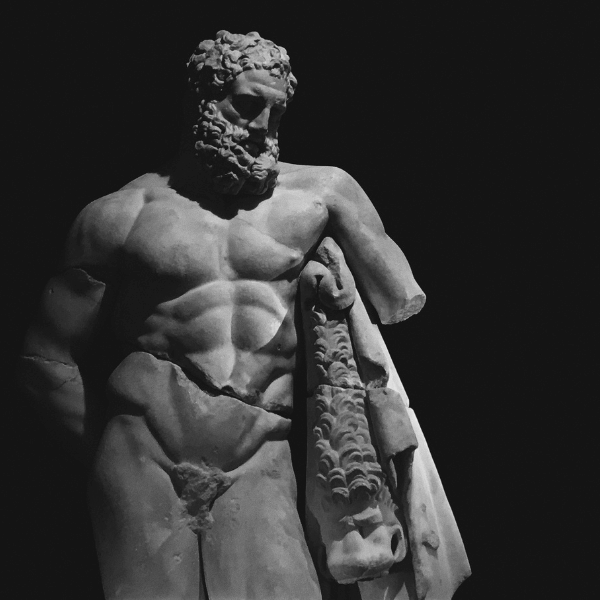 En sofistikerad staty av en äldre stoisk herre i mörkret med perfekt solljus från ovan.