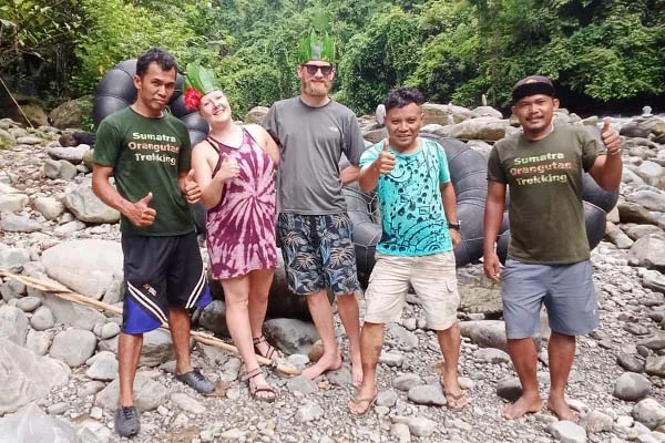 Jungle trekking people and guides smiling happily into the camera with hats made of leafs