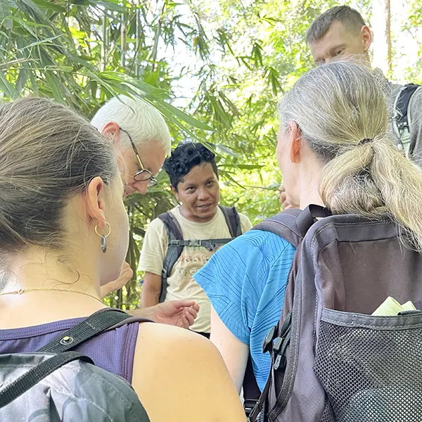 Trekking guide sharing knowledge with attentive hikers in the Sumatran jungle.