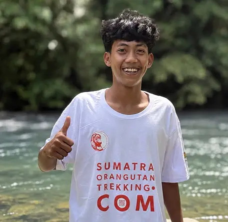Iky smiling and giving a thumbs-up beside the river.