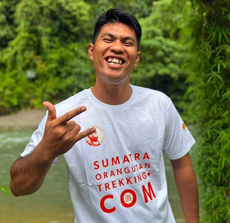 Sandy smiling by the river, wearing a Sumatra Orangutan Trekking T-shirt.