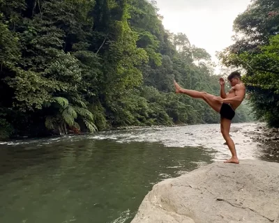 Eco Workout Trekking trainer Dedek is standing on a big rock in the jungle traning Muay Thai