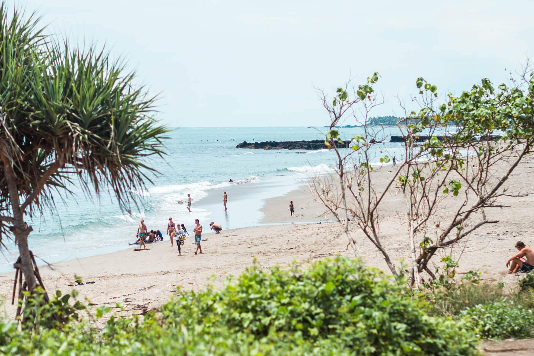 View of people walking along Batu Bolong Beach in Canggu on a sunny day, one of the best places to stay in Bali.