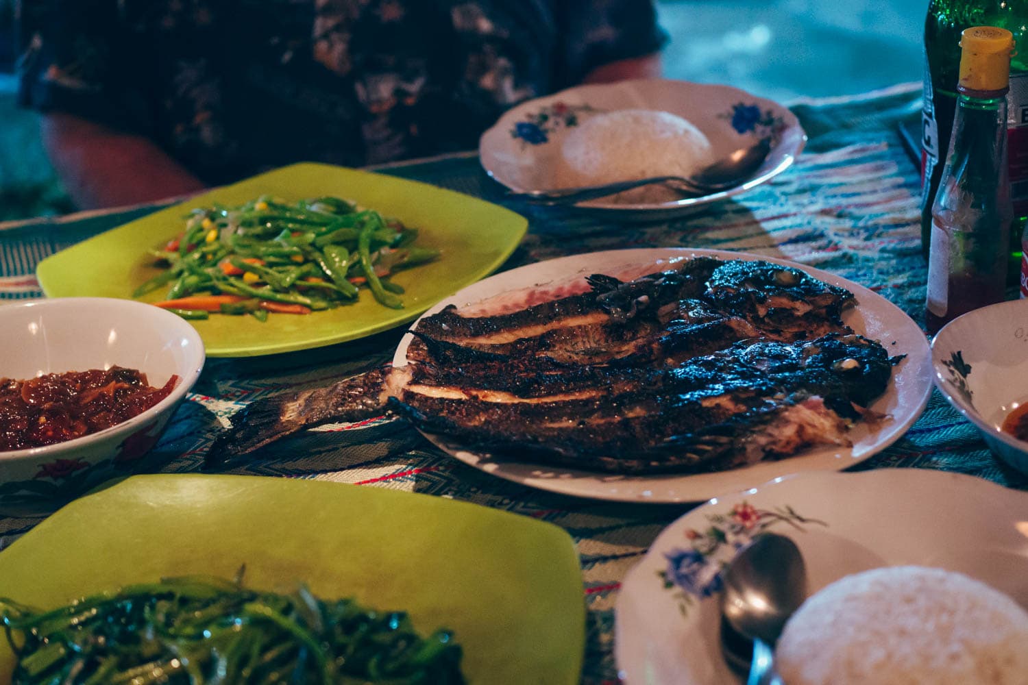 Grilled fish with vegetables and rice served on white and green plates, one of the best things to eat in Lombok.