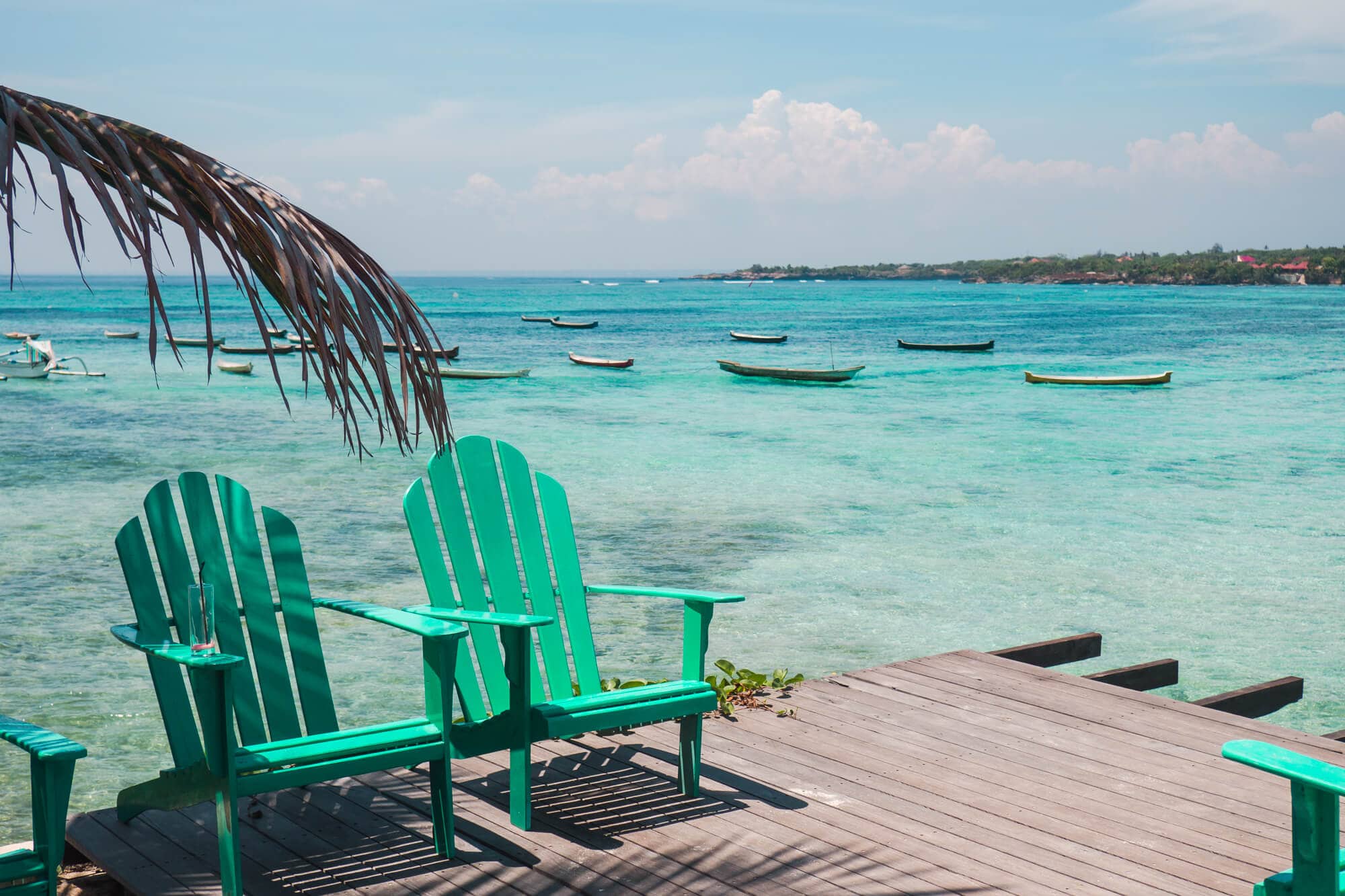 A patio with turquoise chairs down by the water at Le Pirate Beach Club on Nusa Ceningan