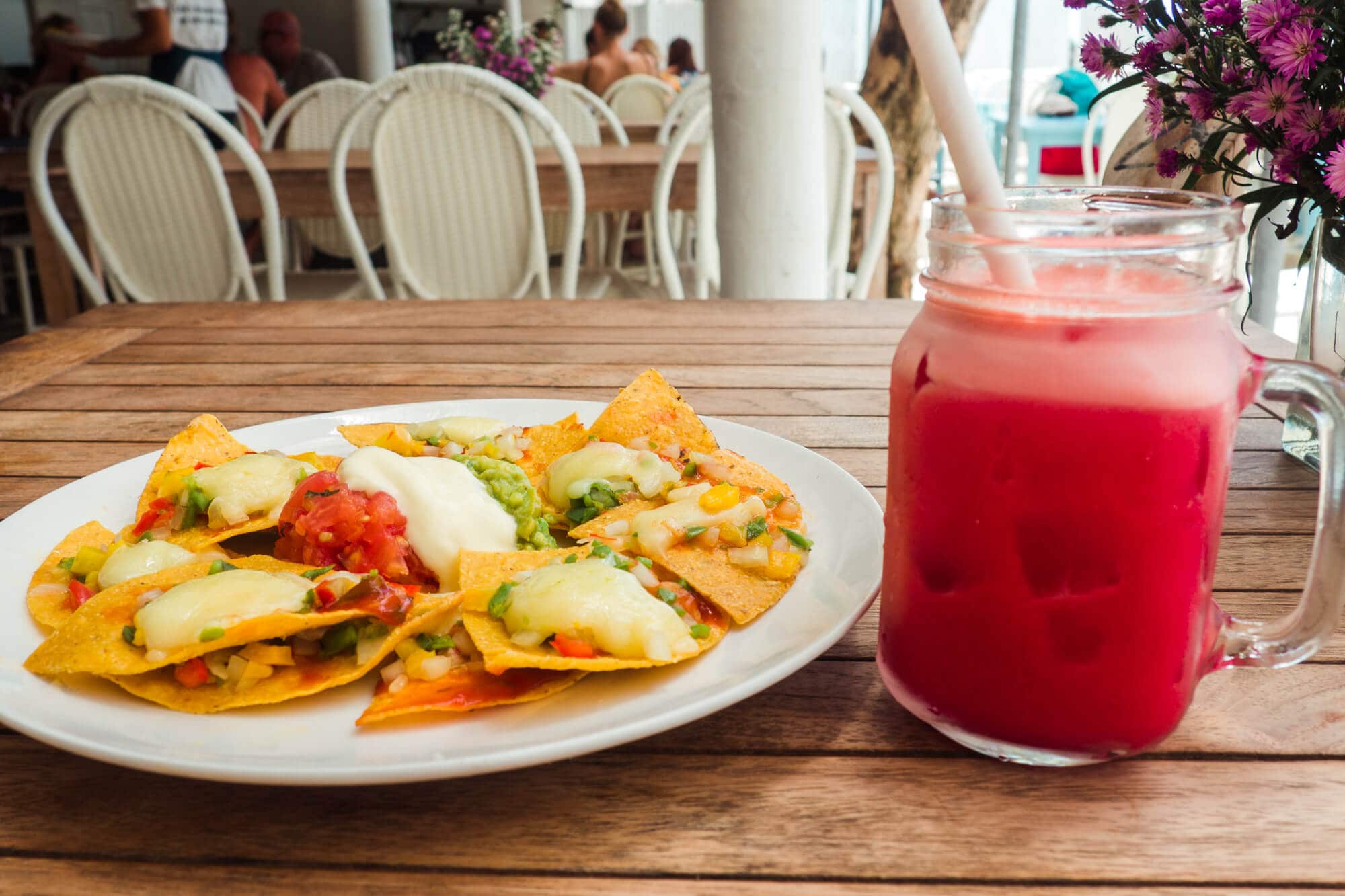 Simple nachos on a white plate with a red fruit juice at Sandy Bay Beach Club on Nusa Lembongan