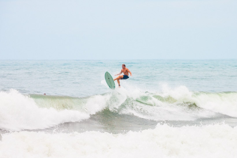 Surfer with a mint green board doing an air in the waves at Echo Beach Canggu Bali