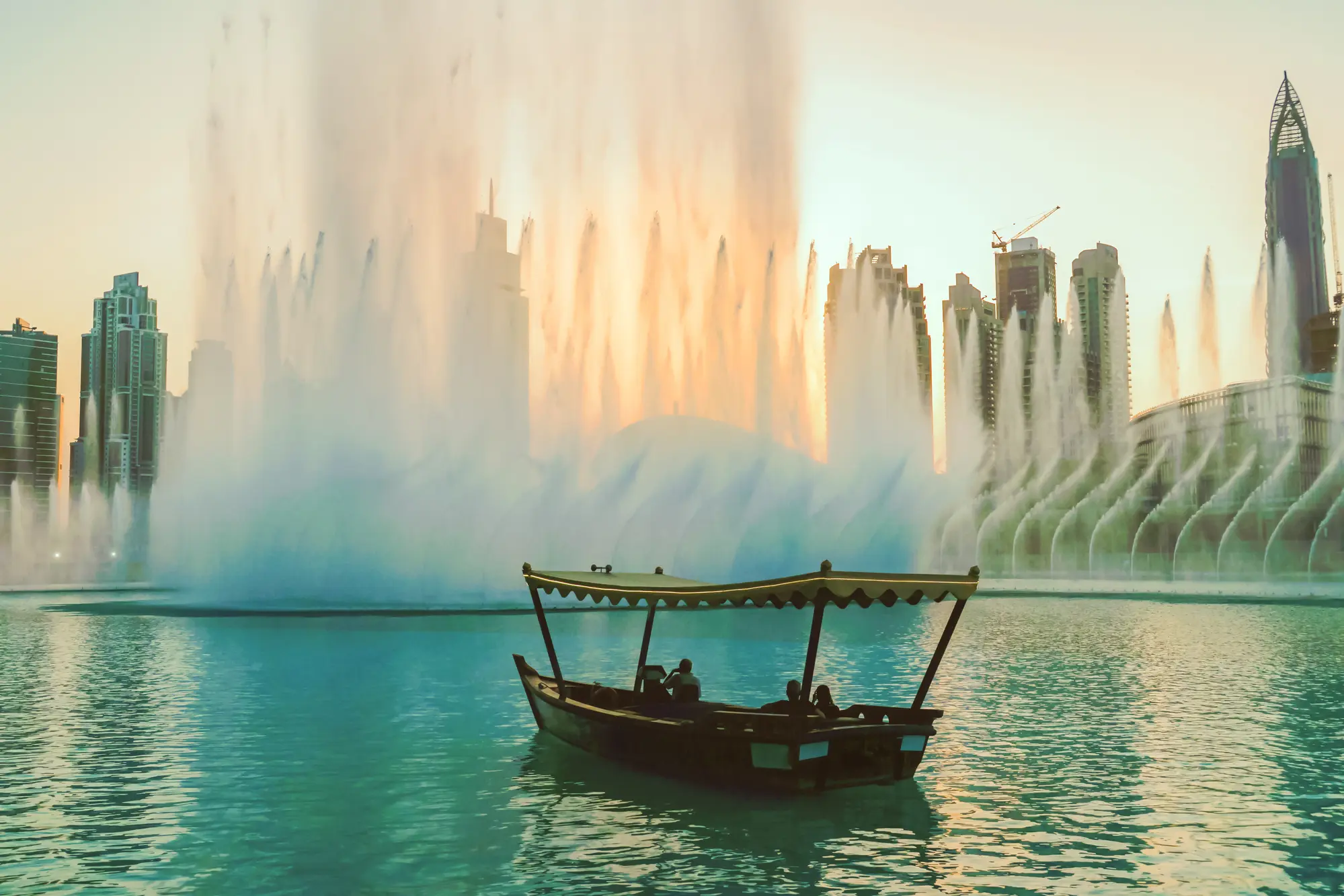 Old traditional wooden boat "Abra" on the lake surrounding the fountain show at Dubai Mall during sunset. A top thing to do during your two days in Dubai.