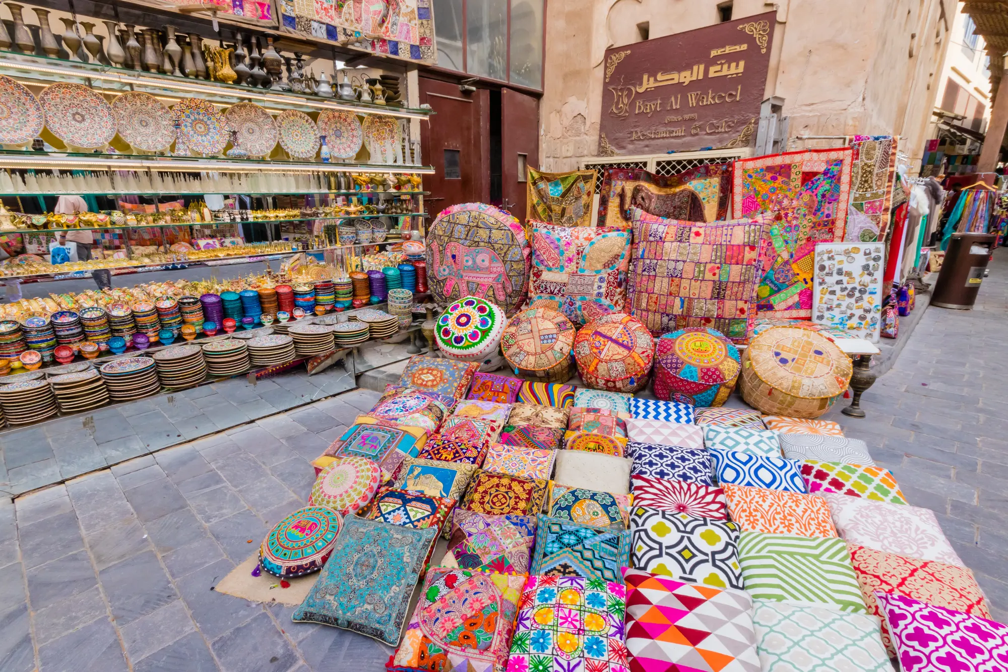 Stall with colorful poufs and souvenirs in the souks of Old Dubai itinerary.